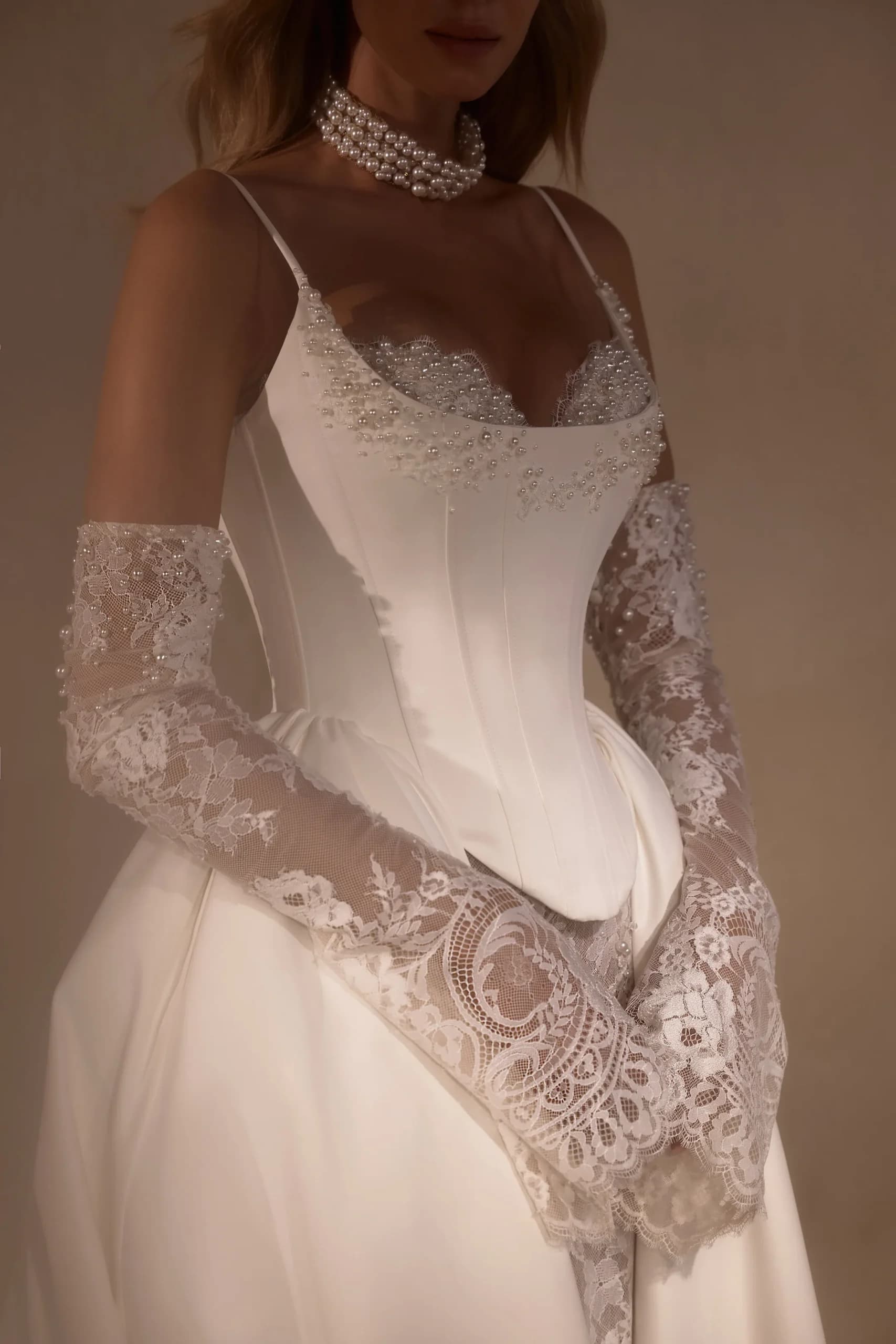 Bride wearing ivory gown with beaded sweetheart neckline, thin straps, and lace sleeves with pearl beading